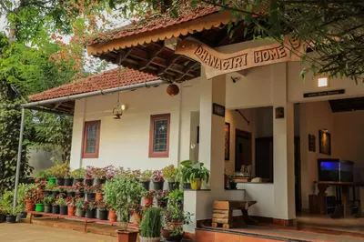 a building with potted plants in front of it at Dhanagiri Homestay Wayanad in Vythiri