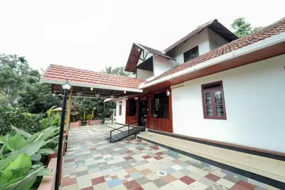 a house with a tiled courtyard in front of it at Wayanad Vista Family Bungalow in Padinjarathara