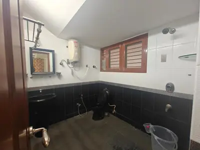 a bathroom with a toilet and a sink and a window at 6bhk Luxury Villa in Mysore