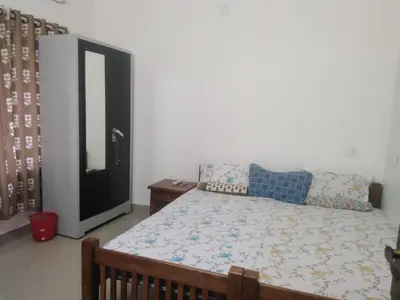 a bedroom with a bed and a dresser and a mirror at 2BHK Flat At Chalakudy Town Konuparamban Residence A1 in Kizhake Chālakudi