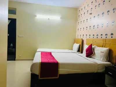 a bedroom with two beds with a pink wall at Avini Stay in Mysore