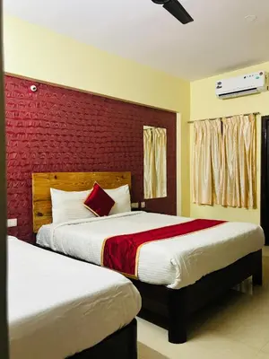a bedroom with two beds and a red wall at Avini Stay in Mysore