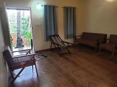 a living room with chairs and a couch and a window at Farmville Riverside in Kakkayam
