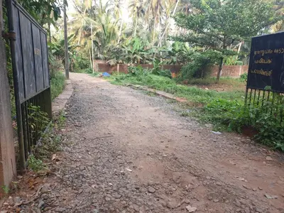 a dirt road with a fence and a sign at Farmville Riverside in Kakkayam