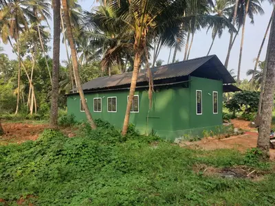 a green house in the middle of palm trees at Farmville Riverside in Kakkayam