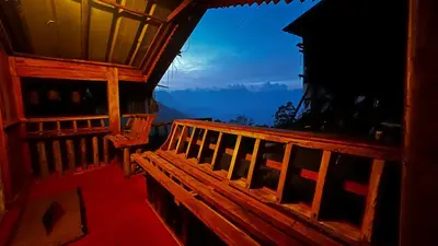 a wooden bench on the balcony of a building at Alpine Mud house Kanthalloor in Kanthalloor
