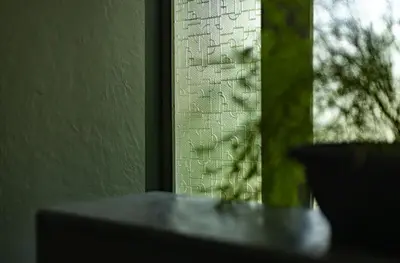 a close up of a glass window with a plant at Malhar - Your Home Beneath The Clouds in Sultan Bathery