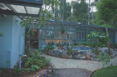 a building with a garden in front of it at Malhar - Your Home Beneath The Clouds in Sultan Bathery
