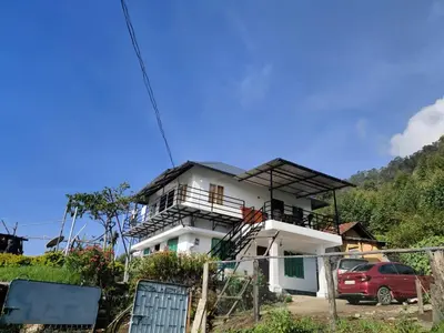 a white house with a car parked in front of it at Drizzling Home Stay in Vattavada