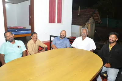 a group of men sitting around a wooden table at Drizzling Home Stay in Vattavada