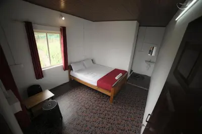 a small bedroom with a bed and a window at Drizzling Home Stay in Vattavada