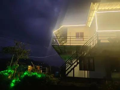 a building with green lights on the side of it at Drizzling Home Stay in Vattavada