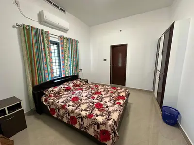 a bedroom with a bed with a floral comforter at The Chill Spot in Karuvapadna