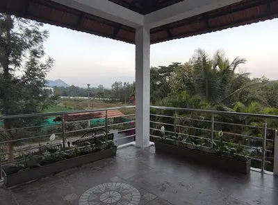 a balcony with plants and a view of the ocean at Coorg Ashiyana in Kushālnagar
