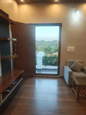 a living room with a couch and a large window at Coorg Ashiyana in Kushālnagar