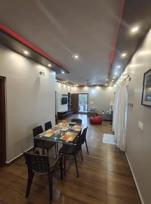 a dining room with a table and chairs and a kitchen at Coorg Ashiyana in Kushālnagar