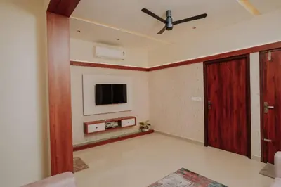 a living room with a ceiling fan and a tv at Atland Residency in Calicut