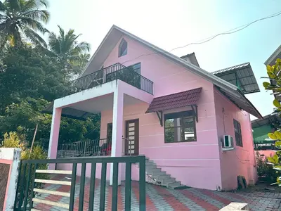 a pink house with a balcony and stairs at Chakkantharas Pool Villas in Athirappilly