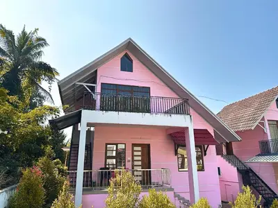 a pink house with a balcony on it at Chakkantharas Pool Villas in Athirappilly