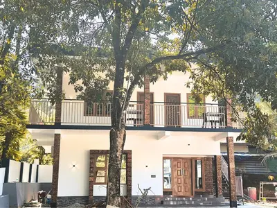 a white house with a balcony and a tree at Chakkantharas Premium Villa in Athirappilly