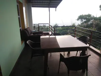 a room with a table and chairs on a balcony at Deep view luxury villa Coffee Cottage Coorg in Madikeri
