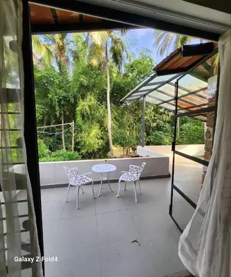 a patio with a table and chairs and trees at RiverMist Resort in Nilambūr