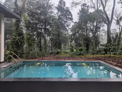 a swimming pool in front of a house at Birdsong Luxury Pool Villa by Luxunlock Private Villas in Suntikoppa