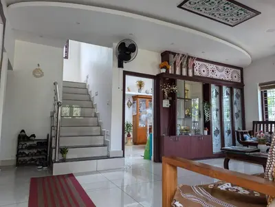 a living room with a staircase in a house at Nadavayal Villa in Wayanad