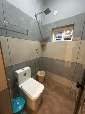a bathroom with a toilet and a window and a shower at Homie Hub in Meppādi