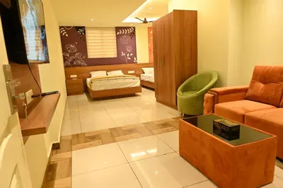 a living room with a couch and a bed at Cous Cous Residency Hotel in Padinjarathara