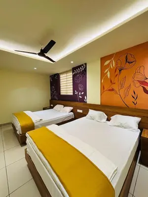 a bedroom with two beds and a painting on the wall at Cous Cous Residency Hotel in Padinjarathara