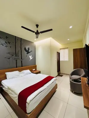 a bedroom with a bed and a desk and a chair at Cous Cous Residency Hotel in Padinjarathara