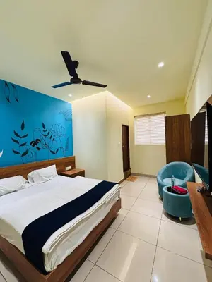 a bedroom with a bed and a blue wall at Cous Cous Residency Hotel in Padinjarathara