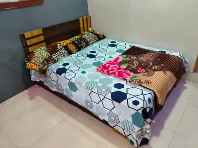 a bed with a colorful comforter and pillows on it at Sri Vinayaka Tourist Home in Nanjangūd