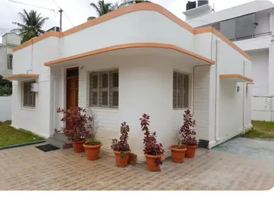 a white house with potted plants in front of it at Perfect Gateway in Mysore