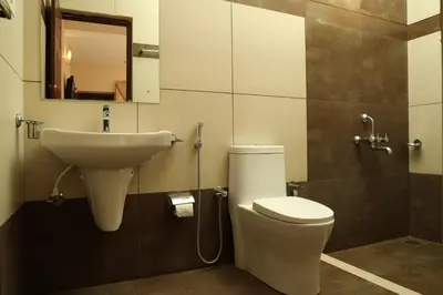 a bathroom with a sink and a toilet and a mirror at Velu's Resort in Gūdalūr
