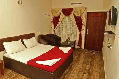 a bedroom with a bed and a couch and a television at Velu's Resort in Gūdalūr