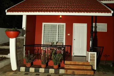 a house with a red wall and some plants at Velu's Resort in Gūdalūr