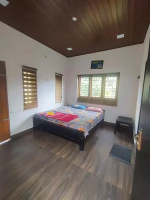 a bedroom with a bed in the middle of a room at Private Cottage Wayanad in Kalpetta