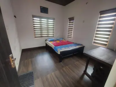 a bedroom with a bed in a room with windows at Private Cottage Wayanad in Kalpetta