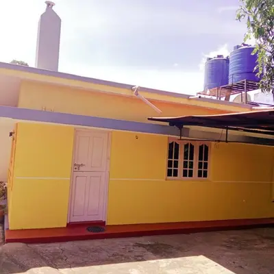 a yellow house with a white door on it at Aghasthyashrya Homestay in Siddapur