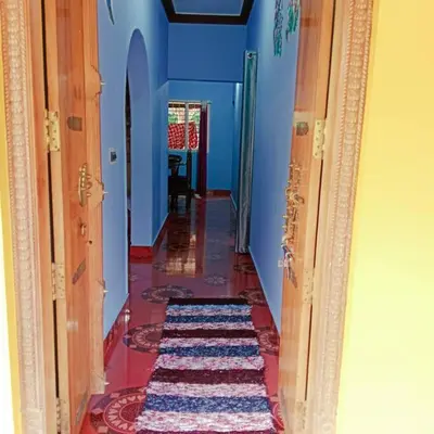 a hallway with a blue room with a rug on the floor at Aghasthyashrya Homestay in Siddapur