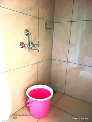 a pink bucket in a bathroom with a faucet at Goldenpeak Estate-Homestay-3Bed-A frame Holiday Home in Wayanad