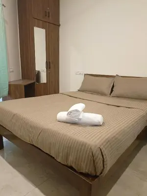 a bed with a white towel on top of it at Ameya Coorg Home Stay in Madikeri