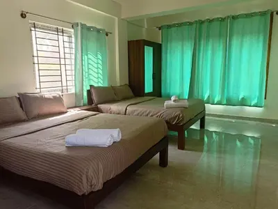 two beds in a room with blue curtains at Ameya Coorg Home Stay in Madikeri
