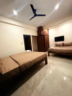 a bedroom with two beds and a ceiling fan at Ameya Coorg Home Stay in Madikeri