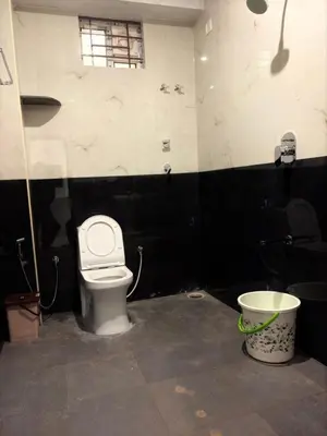 a bathroom with a toilet and a bucket at Ameya Coorg Home Stay in Madikeri