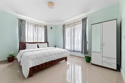 a bedroom with a large bed with a dresser and windows at BVK Mount Home in Ketti