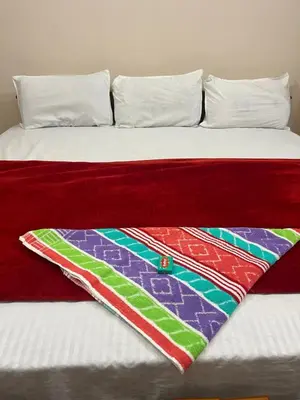 a bed with a colorful blanket on it at VARIYATH HOMESTAY THIRUNELLi in Thirunelli