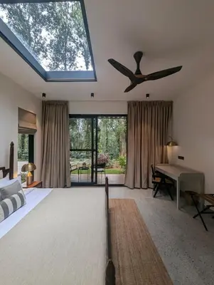 a bedroom with a ceiling fan and a bed and a table at Earthsong Luxury Pool Villa by Luxunlock Private Villas in Suntikoppa